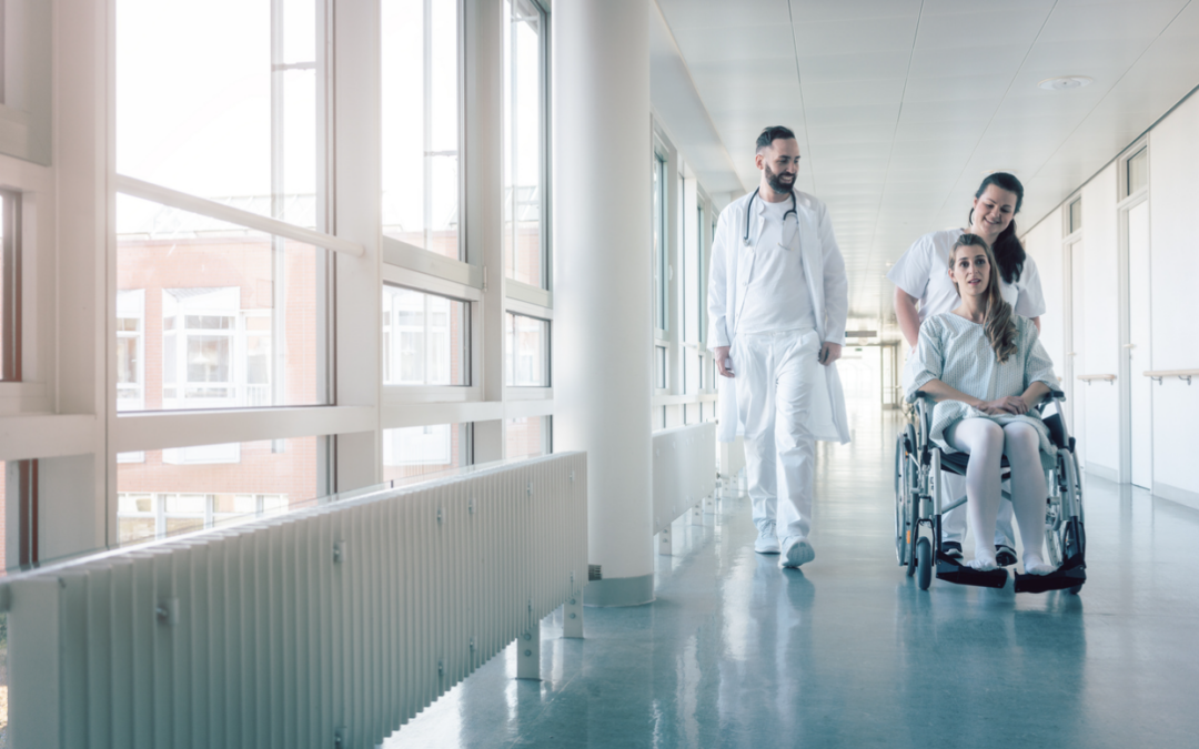 Doctor, nurse, and patient in wheelchair walking in a corridor at a healthcare facility that uses FreMarq products.